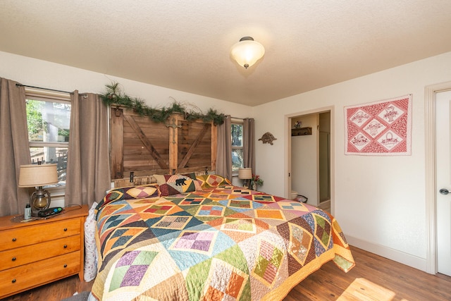 bedroom featuring a textured ceiling and dark hardwood / wood-style flooring