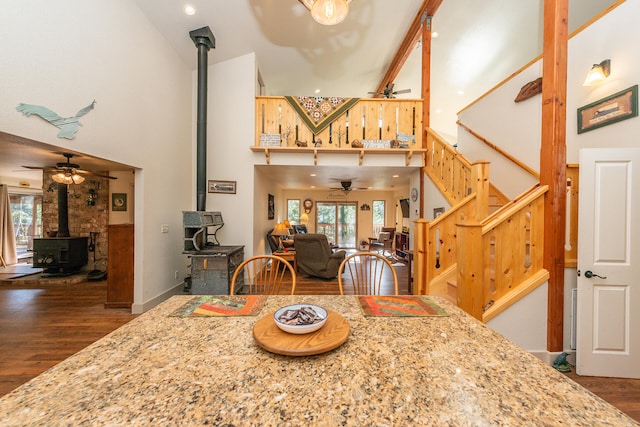 dining space featuring ceiling fan, dark wood-type flooring, and a wood stove