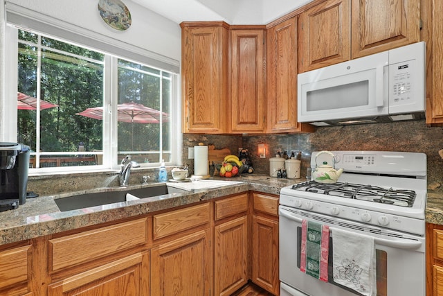 kitchen with white appliances, plenty of natural light, sink, and decorative backsplash