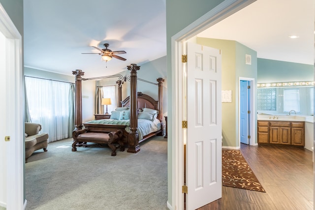 bedroom with ensuite bathroom, ceiling fan, dark carpet, and lofted ceiling