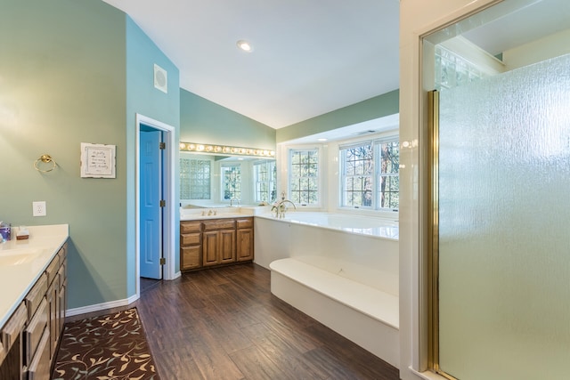 bathroom with vaulted ceiling, separate shower and tub, oversized vanity, and wood-type flooring