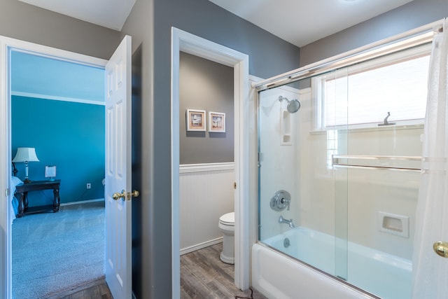 bathroom with toilet, hardwood / wood-style flooring, and bath / shower combo with glass door