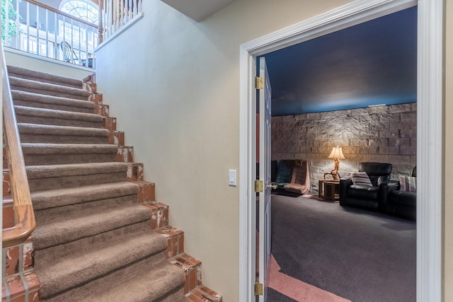 staircase with a fireplace and carpet floors