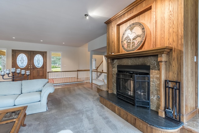 living room featuring a fireplace, wood walls, and dark carpet