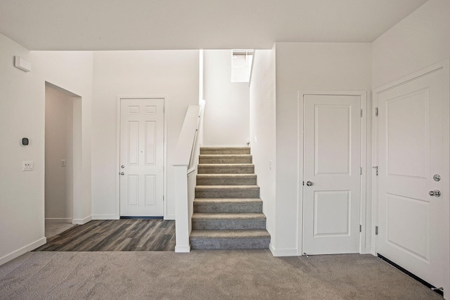 staircase featuring dark carpet