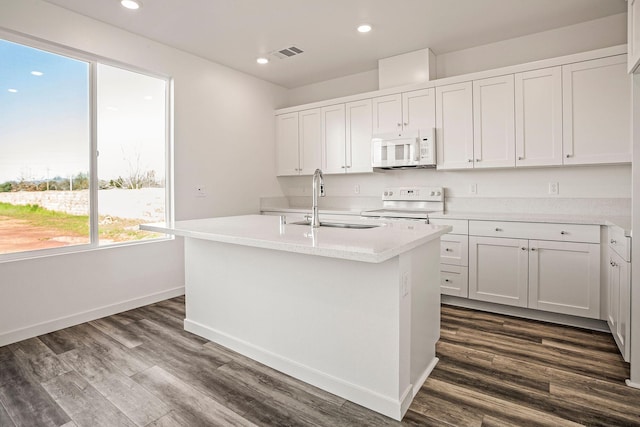 kitchen with white cabinetry, white appliances, dark wood-type flooring, a kitchen island with sink, and sink