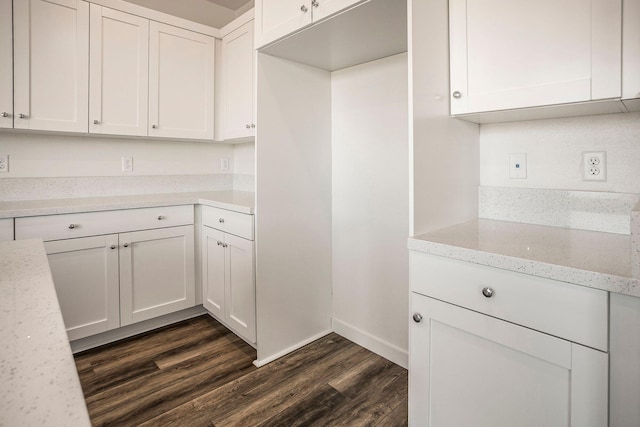 kitchen featuring light stone countertops, white cabinetry, and dark wood-type flooring