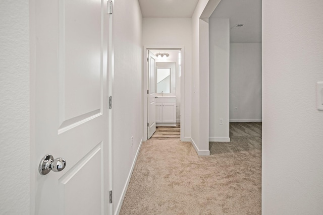 hallway with light carpet and sink