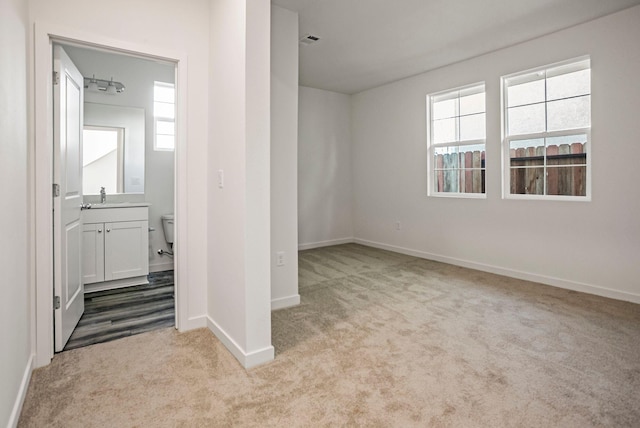 unfurnished bedroom featuring light colored carpet, sink, and multiple windows