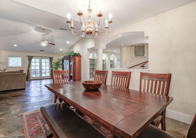 dining room with decorative columns, vaulted ceiling, dark tile flooring, ceiling fan with notable chandelier, and french doors