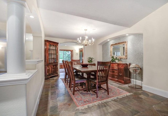 dining space featuring dark tile flooring, an inviting chandelier, and ornate columns