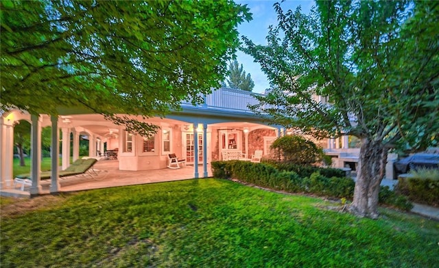 rear view of property featuring a lawn and a patio