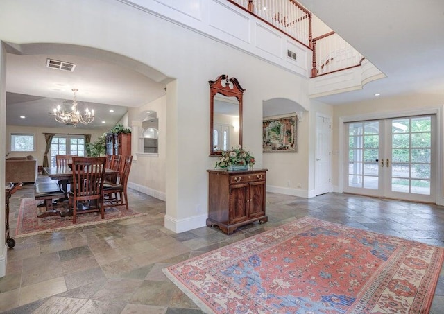 entrance foyer with tile floors, a notable chandelier, and french doors