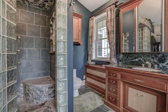 bathroom with vanity, lofted ceiling, tile floors, toilet, and tasteful backsplash