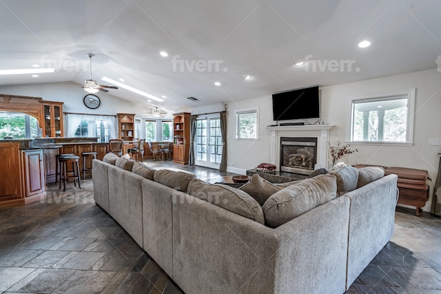 living room featuring lofted ceiling, dark tile flooring, and ceiling fan