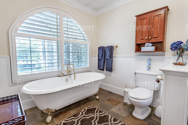 bathroom with plenty of natural light, a bath to relax in, toilet, and ornamental molding