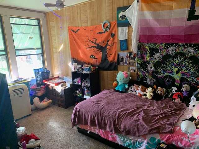 carpeted bedroom with wood walls and ceiling fan