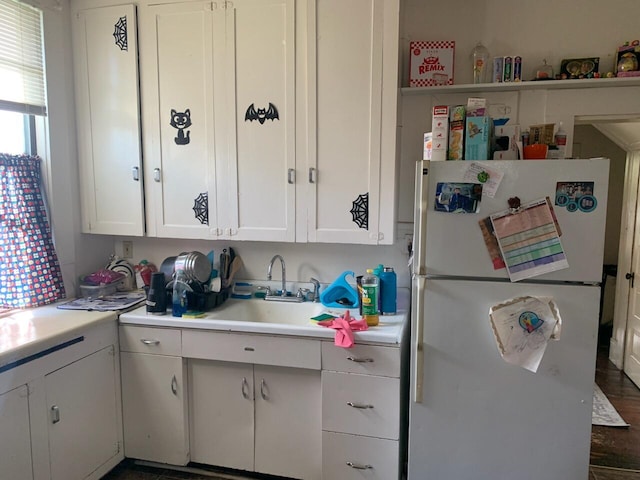 kitchen featuring dark hardwood / wood-style flooring, white cabinetry, white fridge, and sink