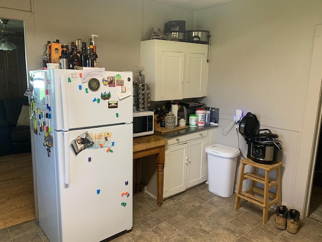 kitchen with white appliances, wood-type flooring, and white cabinets