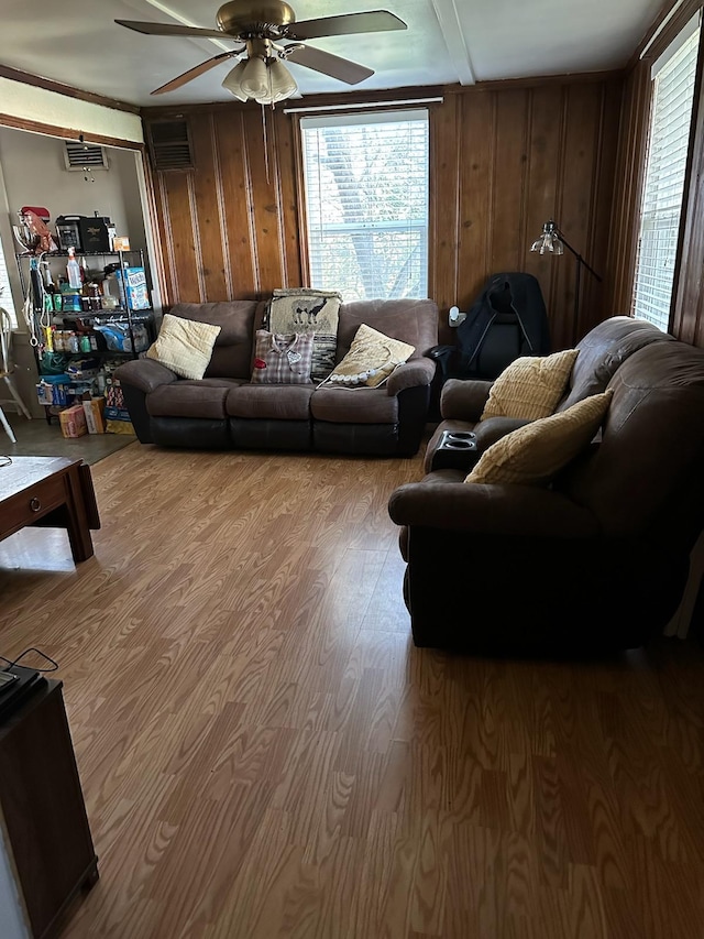 living room with hardwood / wood-style floors, wood walls, and ceiling fan