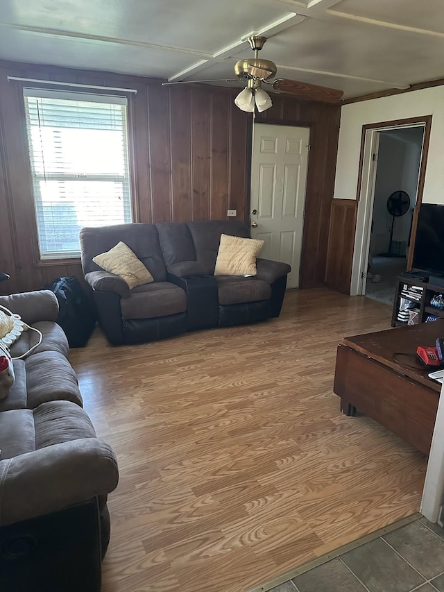 living room featuring ceiling fan, wood walls, and light hardwood / wood-style floors