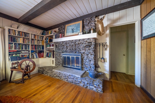 unfurnished living room featuring wood-type flooring, beamed ceiling, a fireplace, built in features, and wooden ceiling