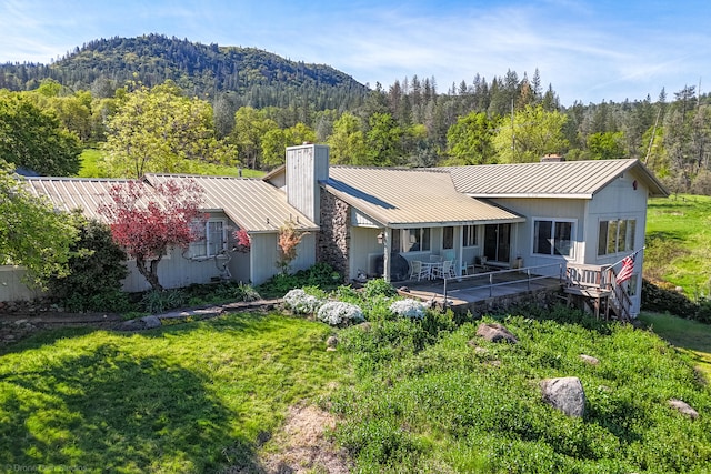 rear view of house with a mountain view and a yard