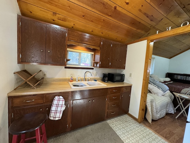 kitchen with dark brown cabinetry, sink, light colored carpet, and wooden ceiling