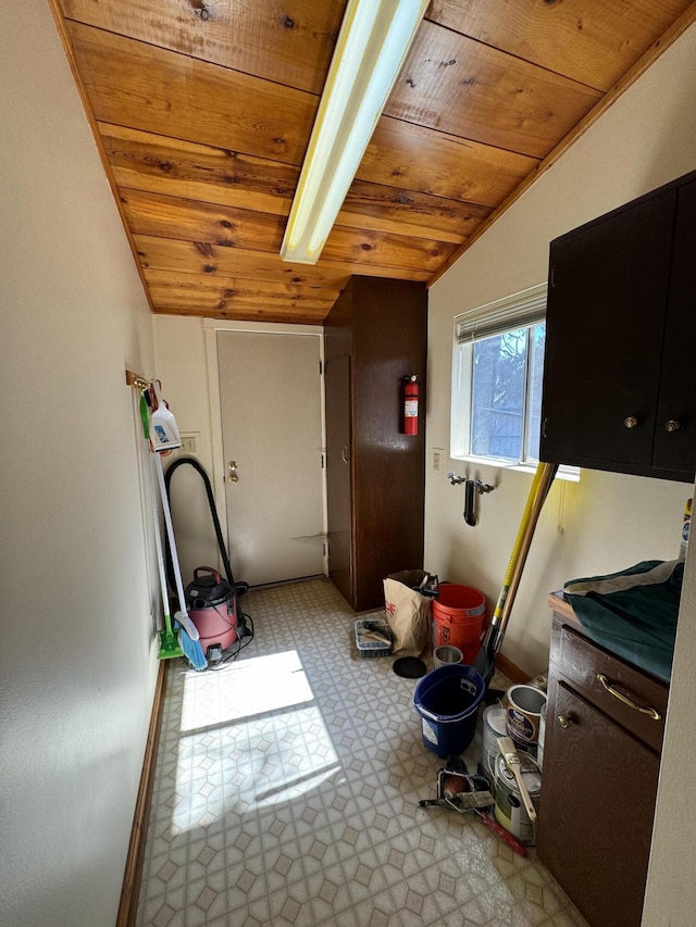 clothes washing area with wooden ceiling and light tile flooring