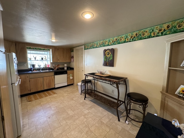 kitchen featuring a textured ceiling, sink, light tile flooring, and white appliances