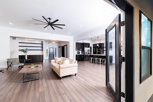 living room featuring ceiling fan, crown molding, and light hardwood / wood-style floors