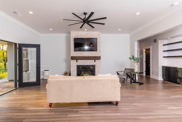 living room with a fireplace, crown molding, hardwood / wood-style flooring, and ceiling fan