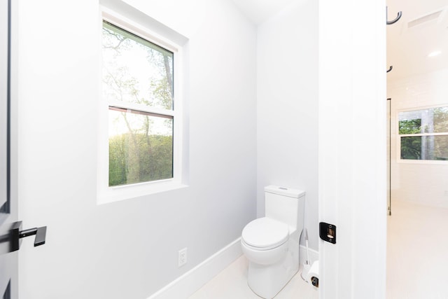 bathroom featuring tile floors, toilet, and a healthy amount of sunlight