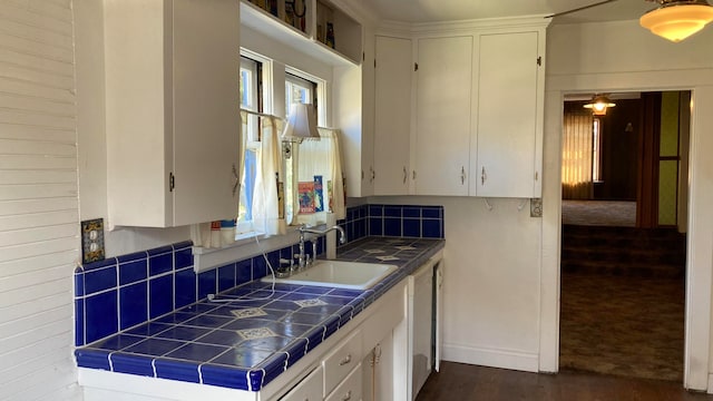 kitchen featuring sink, white cabinets, dark carpet, tile countertops, and tasteful backsplash