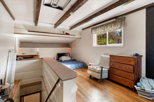 bedroom with light hardwood / wood-style floors and beamed ceiling