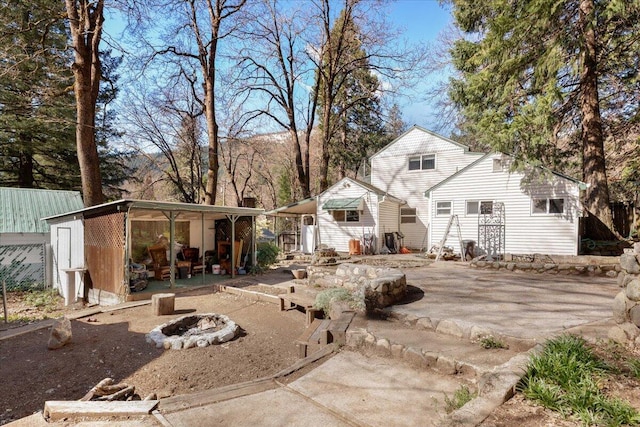 rear view of property featuring an outdoor structure, an outdoor fire pit, and a patio