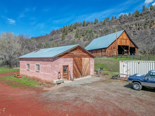 view of property exterior with an outbuilding, a detached garage, a barn, and metal roof