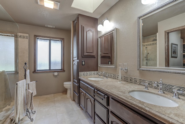 full bath with a sink, toilet, double vanity, and a tile shower