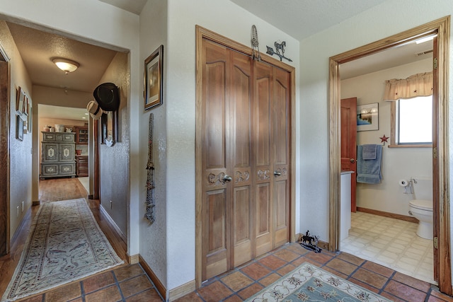 hall featuring visible vents, baseboards, and a textured ceiling