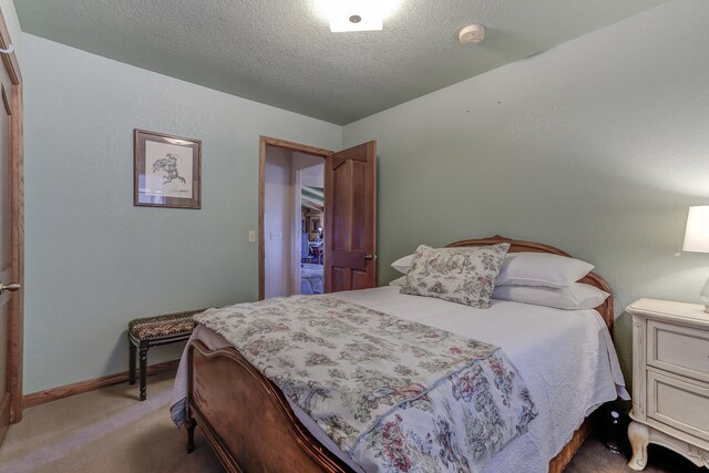 bedroom with light colored carpet, baseboards, and a textured ceiling