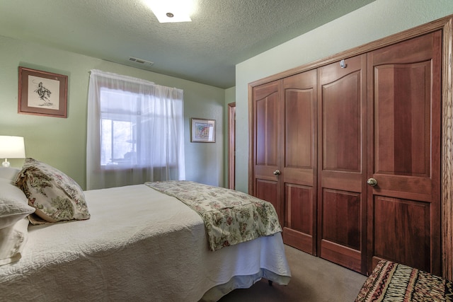 carpeted bedroom with a closet, visible vents, and a textured ceiling