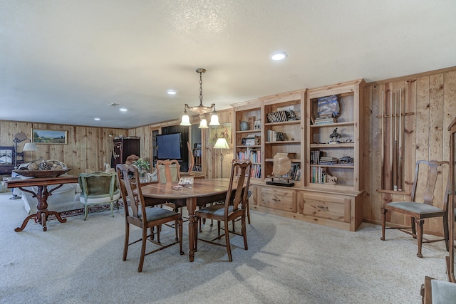 carpeted dining room with recessed lighting and wood walls