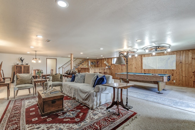 living area featuring billiards, a textured ceiling, carpet floors, wooden walls, and stairs