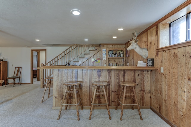 bar with stairway, carpet floors, recessed lighting, indoor wet bar, and wood walls