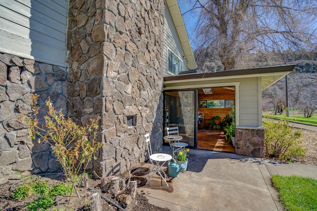 entrance to property with a patio and stone siding