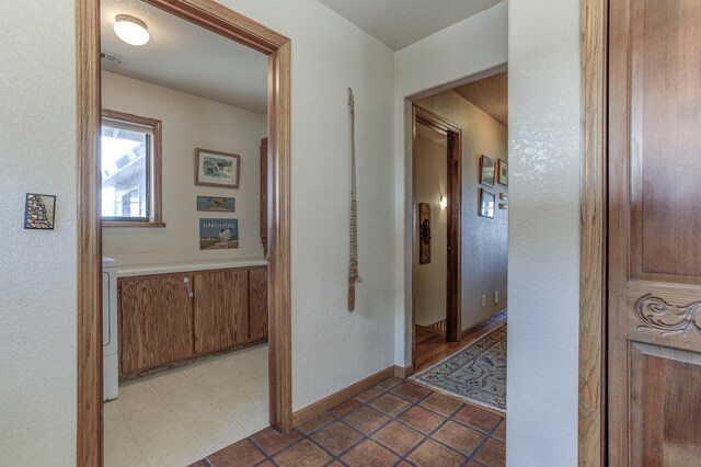 hall with tile patterned floors, visible vents, washer / clothes dryer, and baseboards