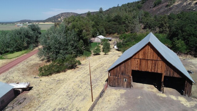 exterior space with a detached garage, a barn, dirt driveway, a mountain view, and an outdoor structure