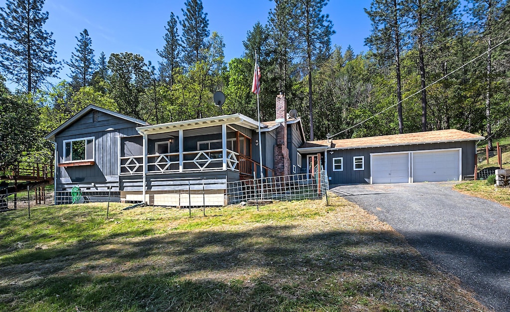 1765 Goose Ranch Rd, Lewiston, CA 96052 - view of front facade featuring aphalt driveway, an attached garage, a sunroom, a front lawn, and a chimney