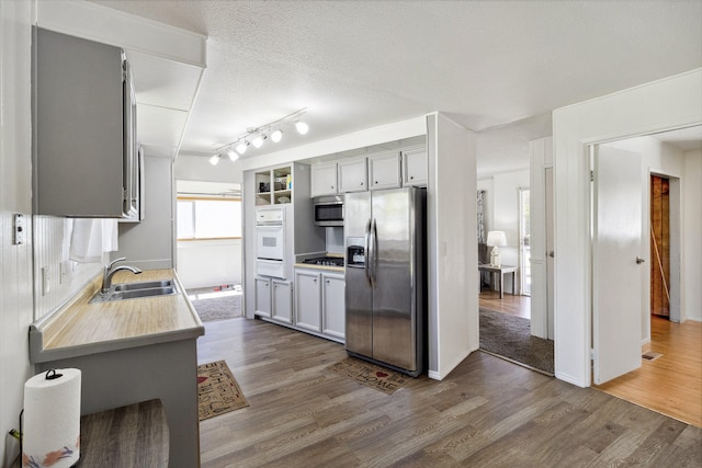 kitchen featuring gray cabinetry, sink, dark wood-type flooring, a textured ceiling, and appliances with stainless steel finishes