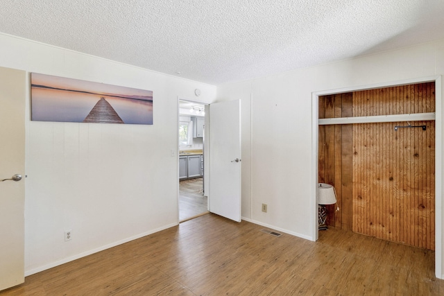 unfurnished bedroom featuring wood-type flooring, a textured ceiling, and a closet